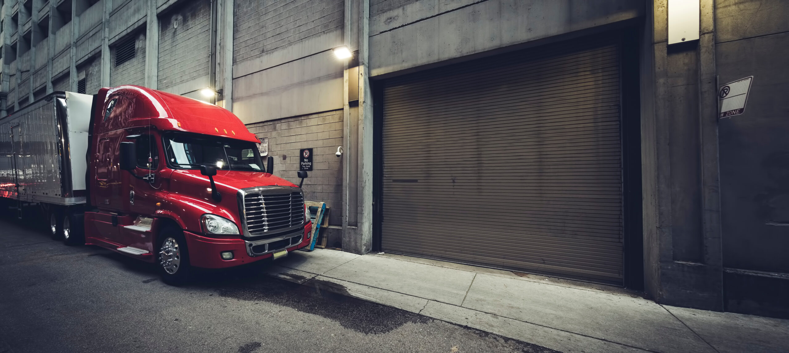 Panoramic truck A picture of a red commercial truck with trailer parked in a back lane in the evening.